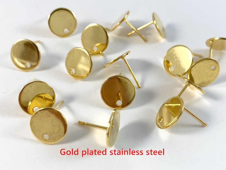 May include: A close-up of gold-plated stainless steel earring findings. The findings are round with a small hole in the center. They are perfect for making your own earrings.