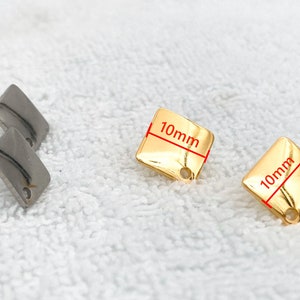 May include: Two pairs of earrings, one pair is silver and the other is gold. The gold earrings are square shaped and measure 10mm by 10mm.