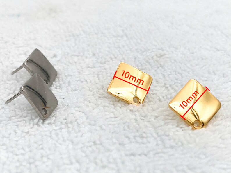 May include: Two pairs of earrings, one pair is silver and the other is gold. The gold earrings are square shaped and measure 10mm by 10mm.