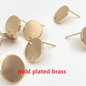 May include: Six gold-plated brass earring blanks with a round shape and a small hole in the center.  The earring blanks are on a white surface.  gold plated brass