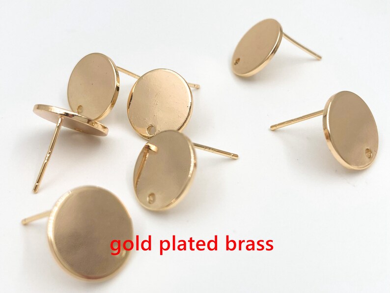 May include: Six gold-plated brass earring blanks with a round shape and a small hole in the center.  The earring blanks are on a white surface.  gold plated brass