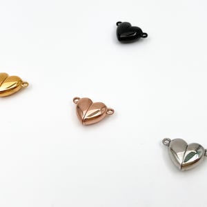 May include: Four heart-shaped magnetic clasps in different finishes: gold, rose gold, silver, and black. These clasps are perfect for jewelry making and can be used to create necklaces, bracelets, and other accessories.