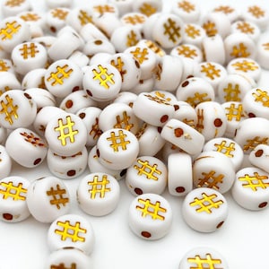 May include: White round beads with a gold hashtag symbol on each bead.