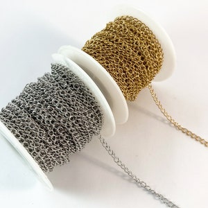 May include: Two spools of chain, one silver and one gold, are shown on a white background. The chain is wound around the spools, and a length of chain is hanging off each spool.