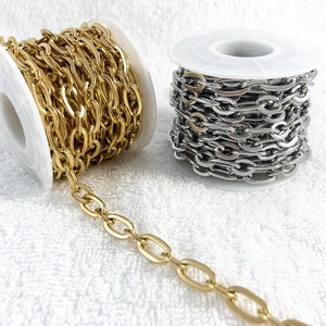 May include: Two spools of chain, one gold-colored and one silver-colored, are displayed against a white background. The chains have an oval link design. The gold chain is unwound slightly, showing the links.
