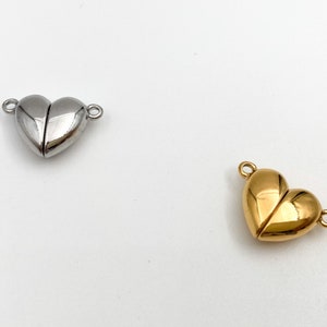 May include: Two heart-shaped magnetic clasps, one silver and one gold, for jewelry making.