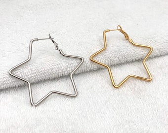 May include: Two pairs of star-shaped hoop earrings. One pair is silver and the other is gold.