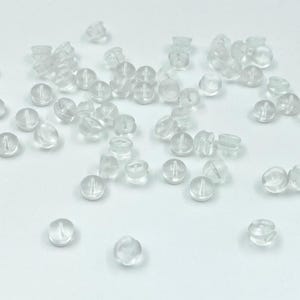 May include: A large quantity of clear plastic earring backs. The backs are small and round with a small hole in the center.