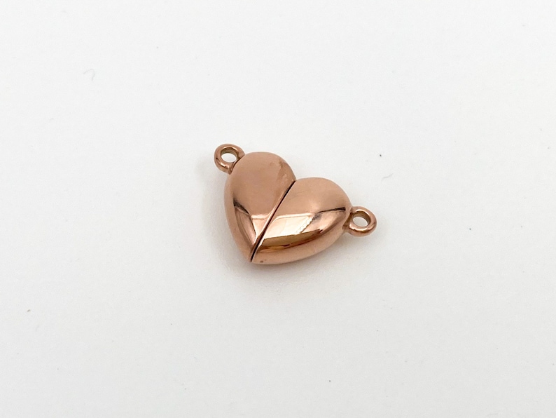 May include: A rose gold heart-shaped magnetic clasp for jewelry making. The clasp is made of metal and has a shiny finish.