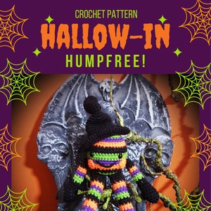 May include: Crochet pattern for a Halloween-themed amigurumi doll. The doll is dressed in black, green, orange, and purple stripes and has a black witch hat. The doll is sitting on a tombstone with bat wings. The pattern is called "Hallow-in" and is "Humpfree!" by Hookanory.