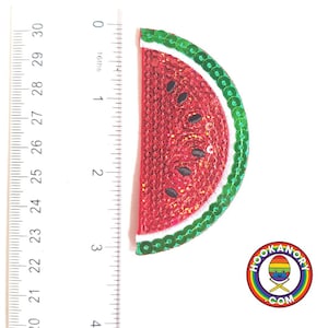 May include: A red watermelon slice with green rind and white seeds, made of sequins, measures approximately 5 cm in diameter.