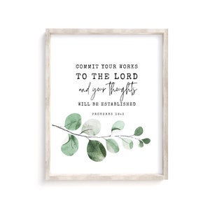 May include: A framed print with a white background and a black text overlay that reads "COMMIT YOUR WORKS TO THE LORD and your thoughts WILL BE ESTABLISHED PROVERBS 16:3". The print features a watercolour illustration of a eucalyptus branch with green leaves.
