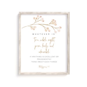 May include: A framed print with a white background and gold text. The text reads "Whatever is True, noble, right, pure, lovely, and admirable." A floral branch with beige berries is at the top. The frame is a light beige color.