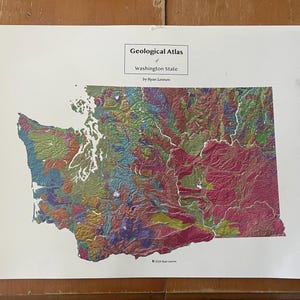 May include: A spiral-bound "Geological Atlas of Washington State" by Ryan Lemmon. The map of Washington State is filled with a variety of colors, including green, pink, purple, and yellow, representing different geological features.