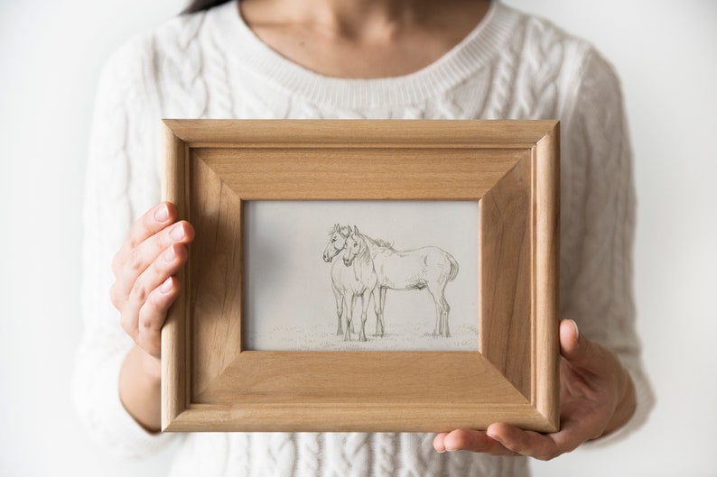 May include: A wooden frame with a black and white pencil drawing of two horses standing side by side.