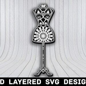 May include: A 3D layered SVG design of a white and black mandala-style dress form on a stand. The design is perfect for crafting and creating unique home decor.