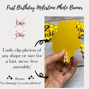May include: A yellow honeycomb-shaped photo banner for a first birthday. The banner includes the text "First Birthday Milestone Photo Banner". The banner is designed to easily clip photos of any shape or size. The text "No damage to your photos!" is also included.