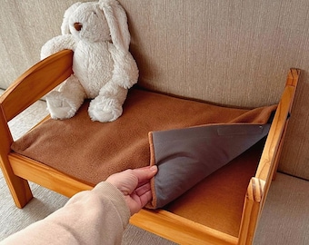 May include: A small wooden pet bed with a brown fleece blanket and a white stuffed bunny. The bed has a simple design with a rectangular frame and a cozy interior, perfect for small pets.