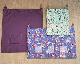 May include: Three fabric hanging bags with metal clips. One is solid purple, the others are patterned. One has a blue floral pattern with foxes, the other has a light green pattern with bunnies. All have clear viewing windows.