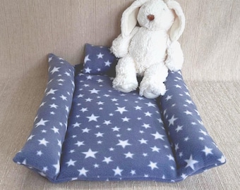 May include: A blue and white star patterned pet bed with a plush white bunny toy. The bed has a raised edge and a removable pillow.