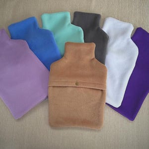 Puede incluir: Siete fundas de botella de agua caliente de forro polar de diferentes colores. Las fundas son de los siguientes colores: morado, azul, verde azulado, marrón, gris, blanco y morado.
