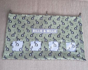 May include: A green fabric hanging organizer with four pockets and a white label that says "Billie & Millie". The fabric has a repeating pattern of black and white rabbits.