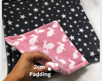 May include: A pet bed with a gray star pattern on one side and a pink bunny pattern on the other. The bed has 2cm padding. The bed is made of soft fleece material.