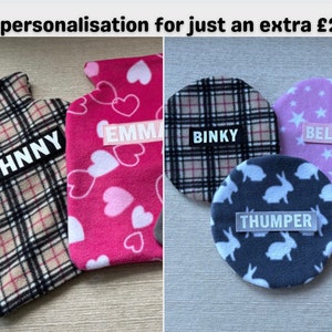 May include: Three personalised hot water bottles with different patterns and names. The first is plaid with the name "JOHNNY", the second is pink with hearts and the name "EMMA", and the third is plaid with the name "BINKY".