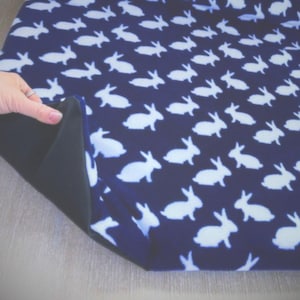 May include: A blue fabric with a white bunny pattern. The fabric is folded over to show the dark blue underside.