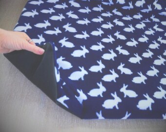 May include: A blue fabric with a white bunny pattern. The fabric is folded over to show the dark blue underside.