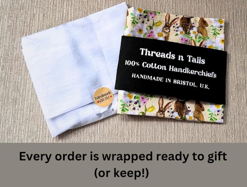 May include: A white tissue paper wrapping with a brown label that says "handmade with love". The tissue paper is wrapped around a handkerchief with a floral pattern and a black label that says "Threads n Tails 100% Cotton Handkerchiefs HANDMADE IN BRISTOL, U.K."