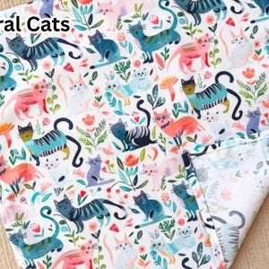 May include: White fabric with a repeating pattern of colorful cats and floral elements. The cats are in various poses and colors, including blue, pink, and teal. The text "Floral Cats" is in the upper left corner.