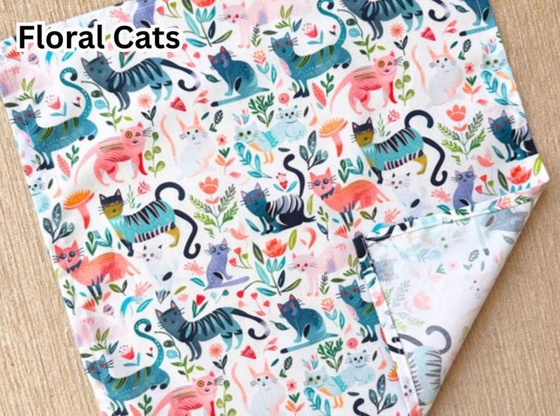 May include: White fabric with a repeating pattern of colorful cats and floral elements. The cats are in various poses and colors, including blue, pink, and teal. The text "Floral Cats" is in the upper left corner.