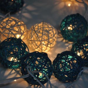 May include: String lights with white and blue woven ball-shaped lights. The lights are strung together with clear wire.