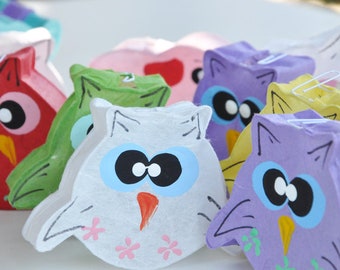 May include: A row of colorful paper mache owl pinatas, each with a different color and design. The owls have large eyes, beaks, and wings.