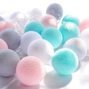 Könnte beinhalten: Eine Lichterkette aus Baumwollkugeln mit einem Mix aus weißen, grauen und hellblauen Kugeln.