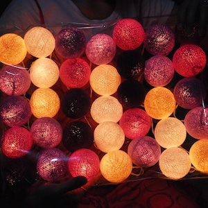 Peut inclure: Une guirlande de lumières en coton de différentes couleurs, dont le blanc, le rose, l'orange, le violet et le rouge. Les lumières sont reliées par un fil transparent et sont parfaites pour ajouter une touche de fantaisie à n'importe quel espace.