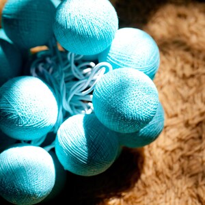 May include: A string of blue cotton ball lights, perfect for adding a touch of whimsy to any space.