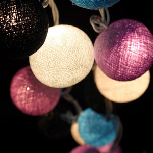 May include: A string of cotton ball lights with a variety of colors, including white, blue, purple, and black.