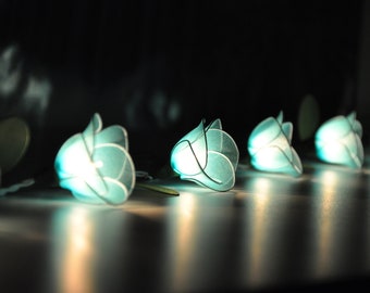 May include: A string of teal blue lights shaped like roses, glowing softly in the dark.