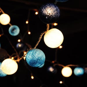 May include: String of lights with white and blue cotton ball lights. The lights are strung together with clear wire.