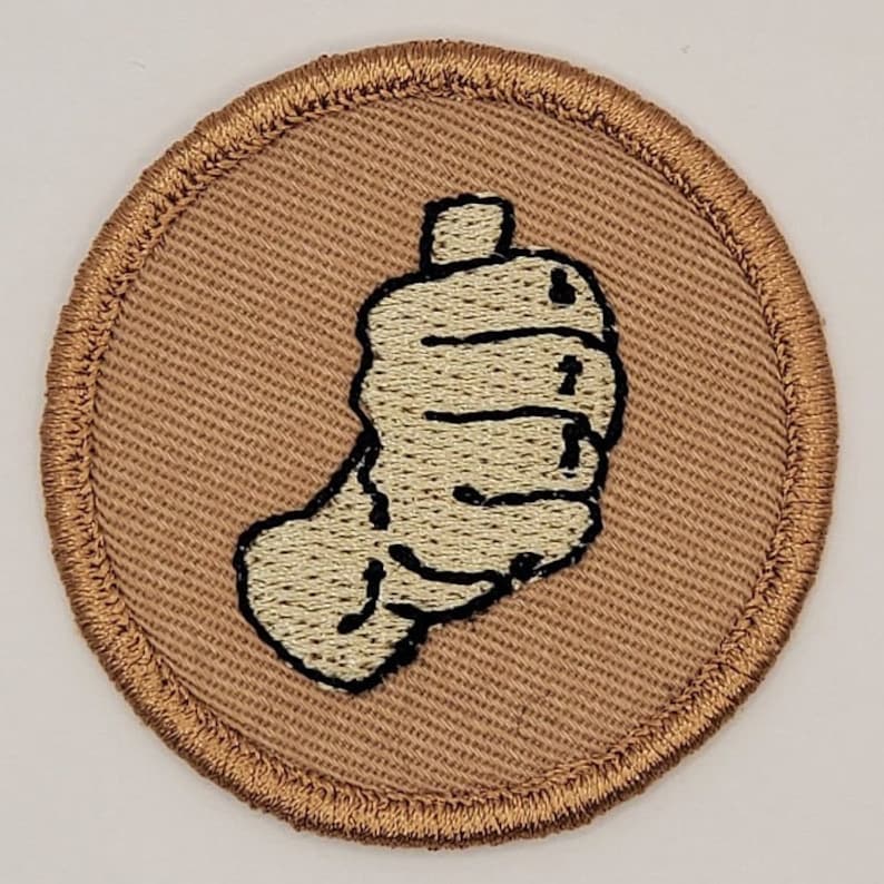 May include: A brown embroidered patch with a white hand giving a thumbs up.