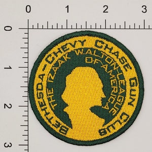 Op de afbeelding: Groen en geel geborduurd patch met de tekst "Bethesda-The Izaak Walton League of America Chase Gun Club".