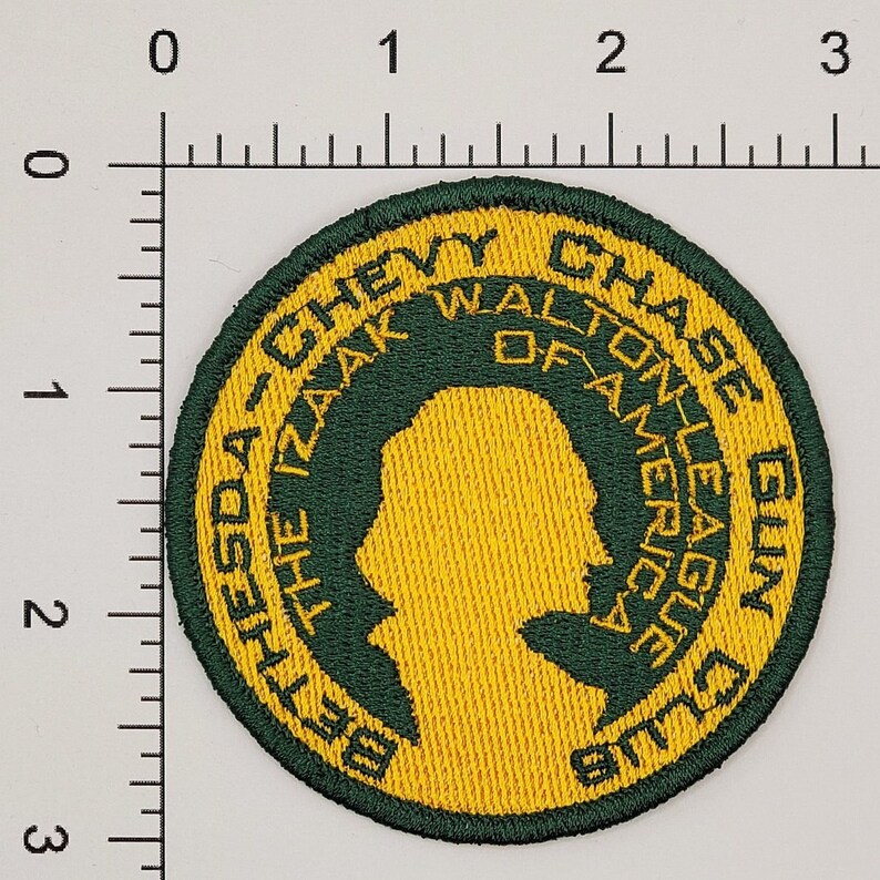 Op de afbeelding: Groen en geel geborduurd patch met de tekst "Bethesda-The Izaak Walton League of America Chase Gun Club".