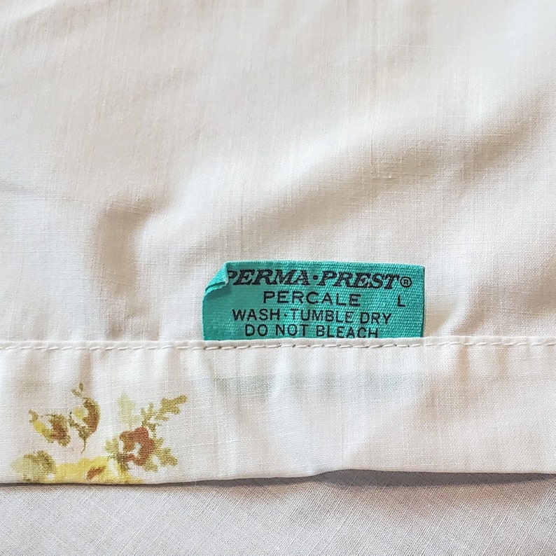 May include: A turquoise blue fabric label with black text that reads "PERMA-PREST&reg; PERCALE WASH TUMBLE DRY DO NOT BLEACH"