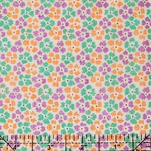 May include: A fabric with a repeating floral pattern in orange, purple, and green on a cream background. The image includes a ruler at the bottom, showing measurements in inches, which are equivalent to centimetres.