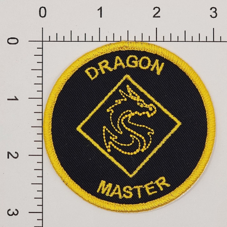 May include: A black and gold embroidered patch with the words "Dragon Master" and a yellow dragon design.