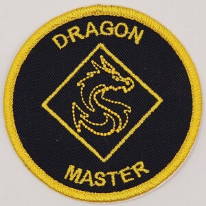 May include: A black and gold embroidered patch with a dragon design and the text "Dragon Master".