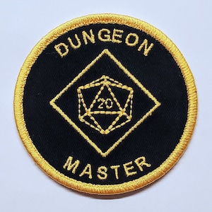 May include: A black and gold embroidered patch with the words "Dungeon Master" and a 20-sided die in the center.
