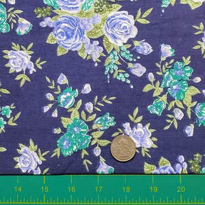 May include: A close-up of a navy blue fabric with a white and green floral pattern. A US quarter is included for scale.